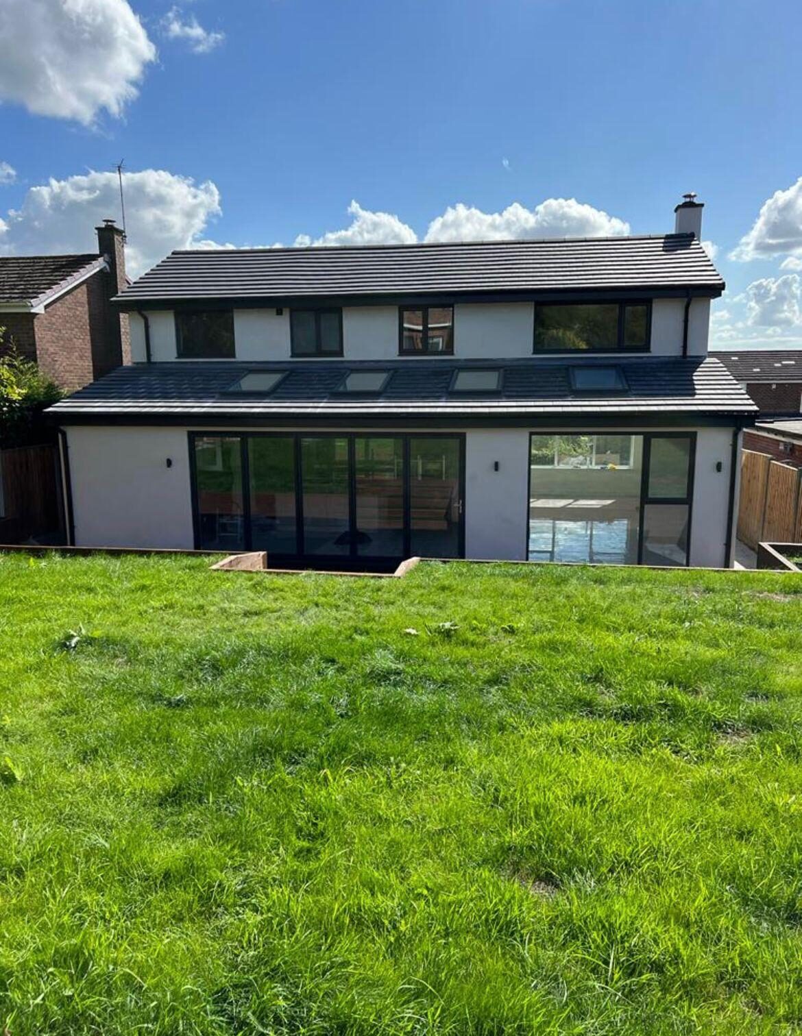 Anthracite aluminium sliding doors and roof glazing on a rear house extension
