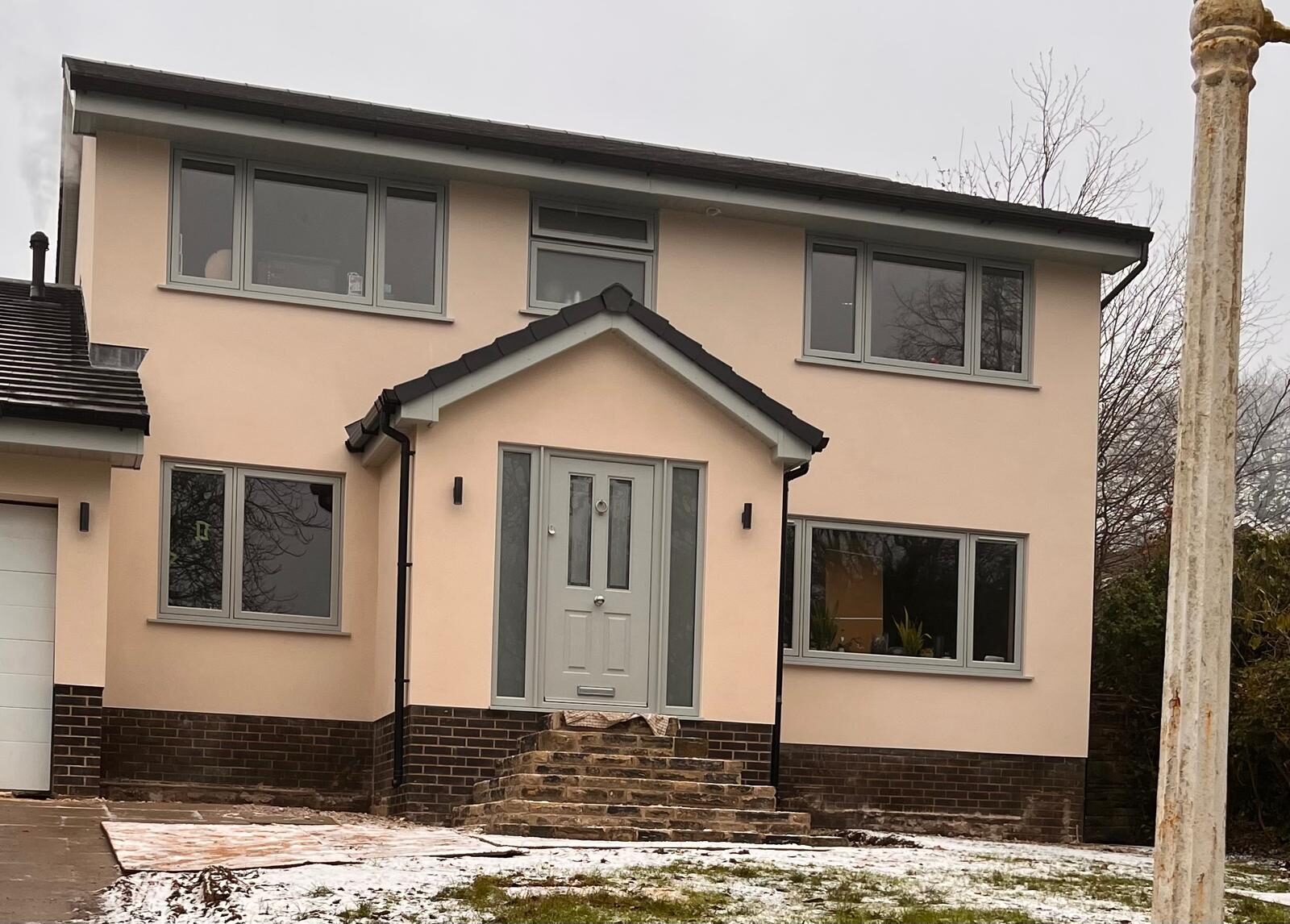 Sage green uPVC windows and matching composite front door on a rendered detached home