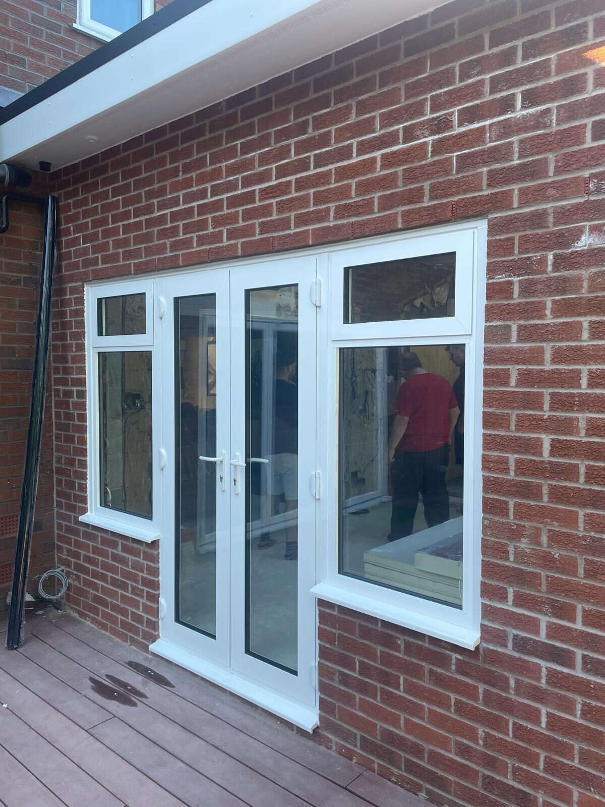 White uPVC French doors with glazed side panels in a brick wall