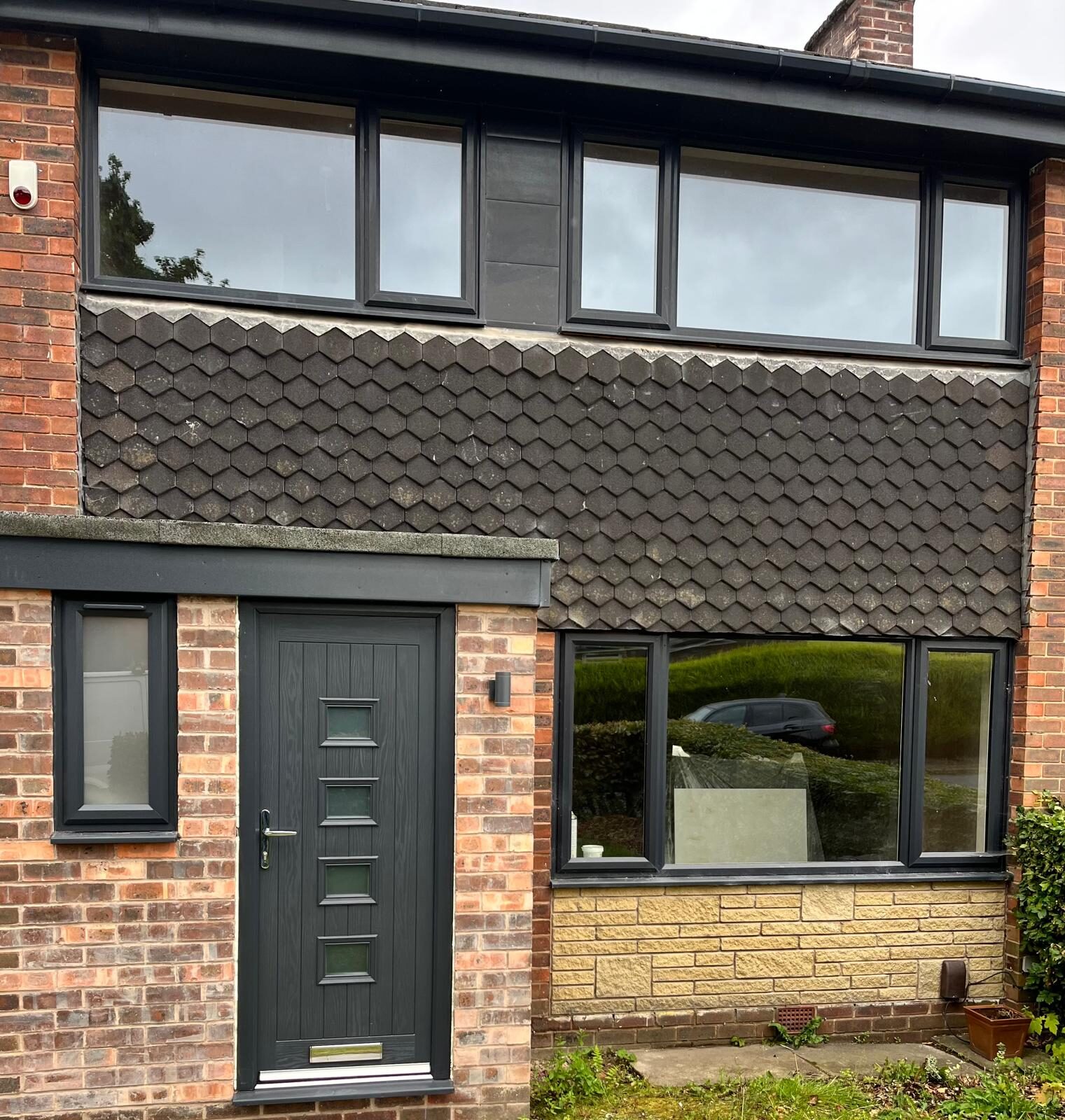 Anthracite composite front door with square glazed panels on a brick house