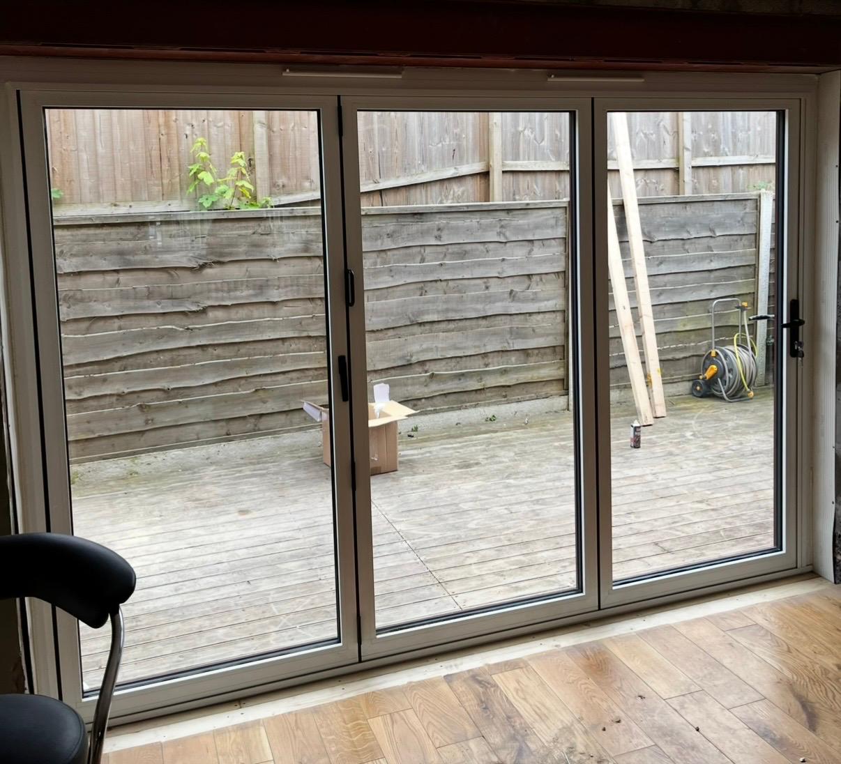 Cream uPVC three-panel bi-folding doors viewed from inside a room onto decking