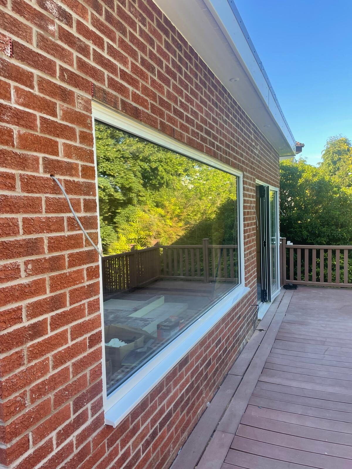 Large fixed picture window installed in a brick extension overlooking decking